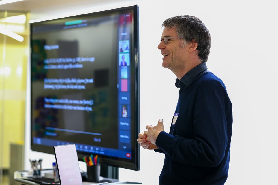 A man stands with a large screen with text on it