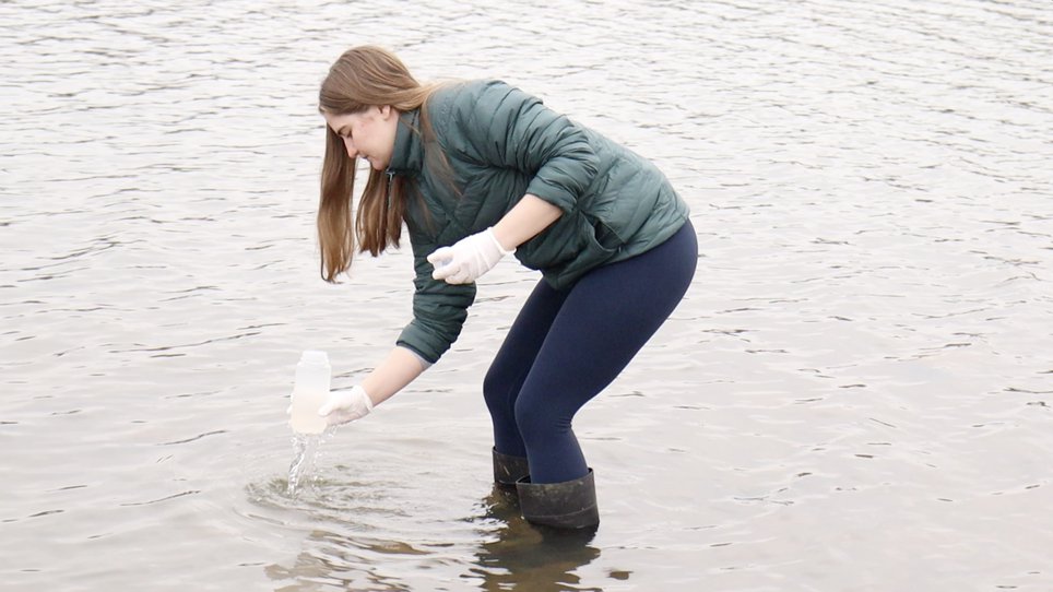 Jessica Lambert gathering a sample of water from a lake.