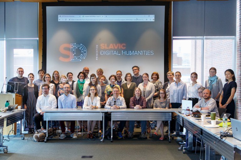 A large group of people gather in front of a screen that reads "Princeton Slavic Digital Humanities"