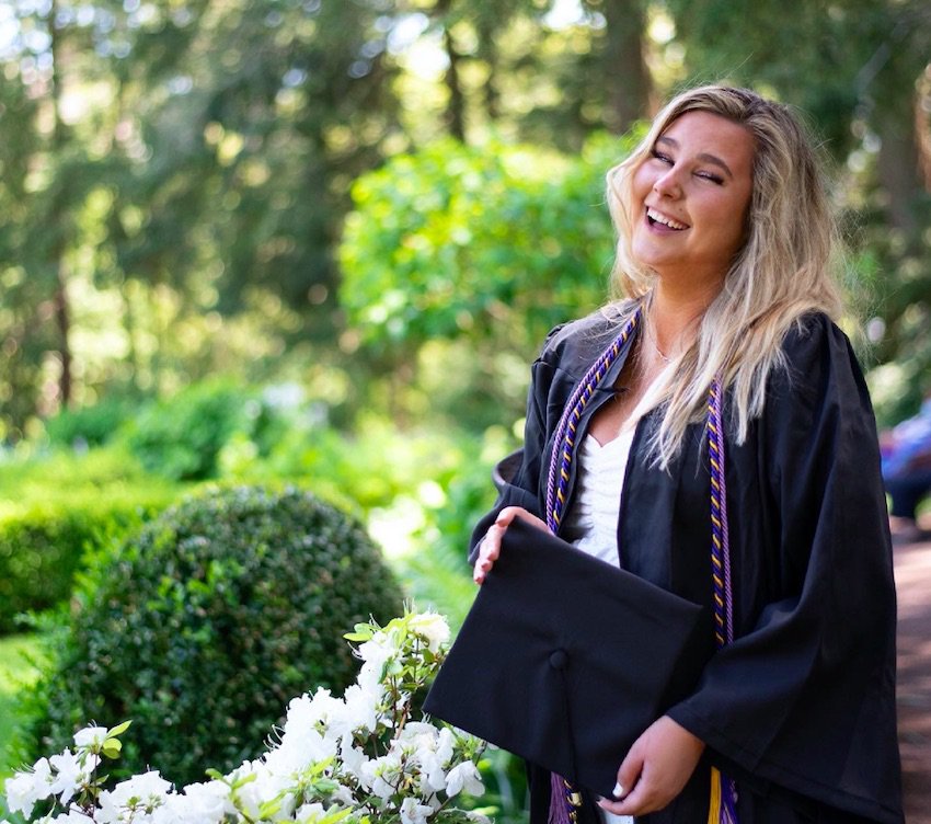 Ara Eagan smiles at the camera while wearing a graduation robe.