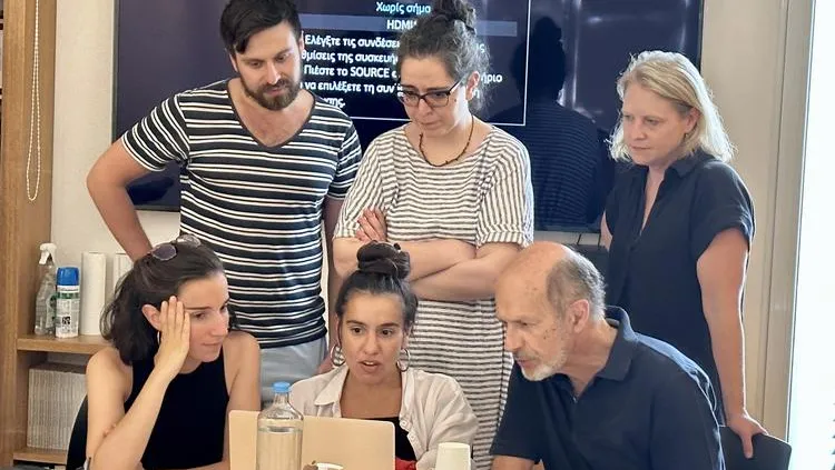 Six people gather around a laptop