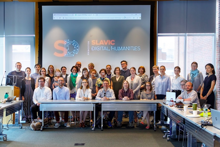 A group of adults stand in front of a screen reading "Princeton Slavic Digital Humanities."